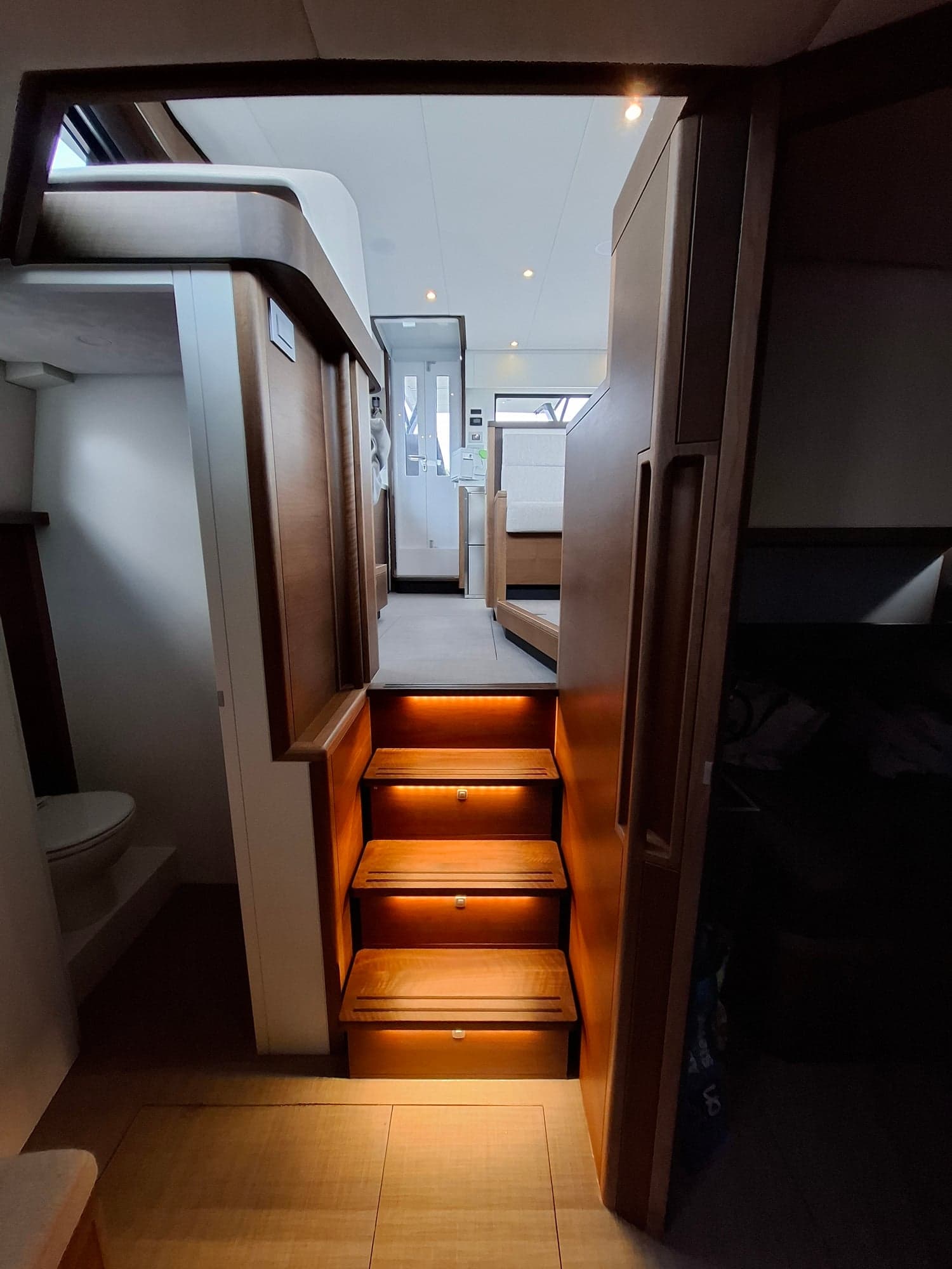 Verlichte houten trap op maat met uitzicht door naar de salon